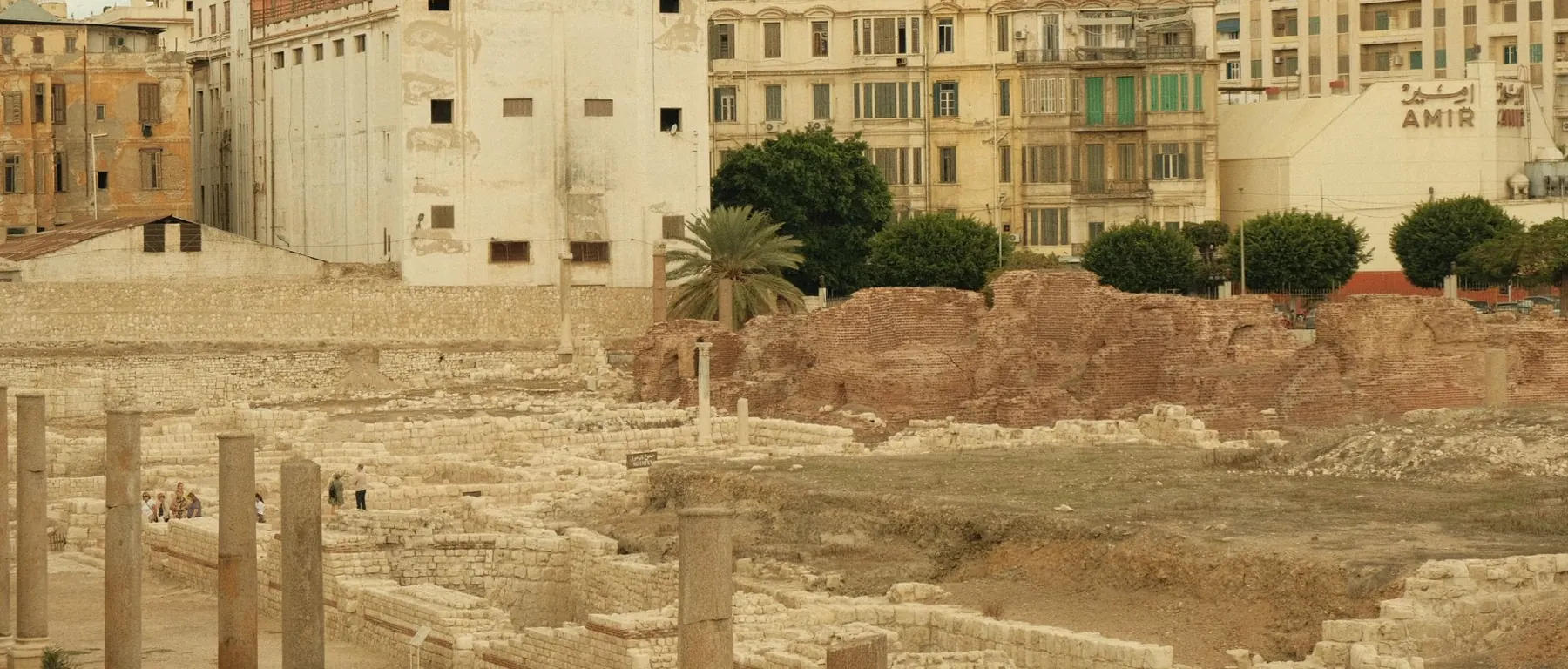 View of ancient Roman ruins against a modern urban backdrop, capturing history's blend with contemporary architecture.