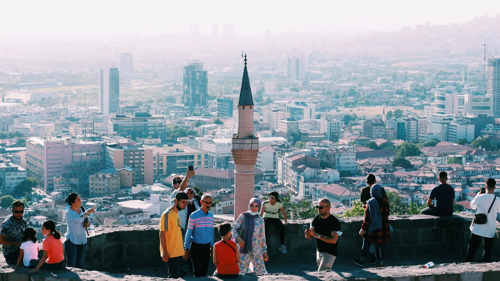 Visitors at Ankara Citadel overlooking the city and a slender foreground minaret.
