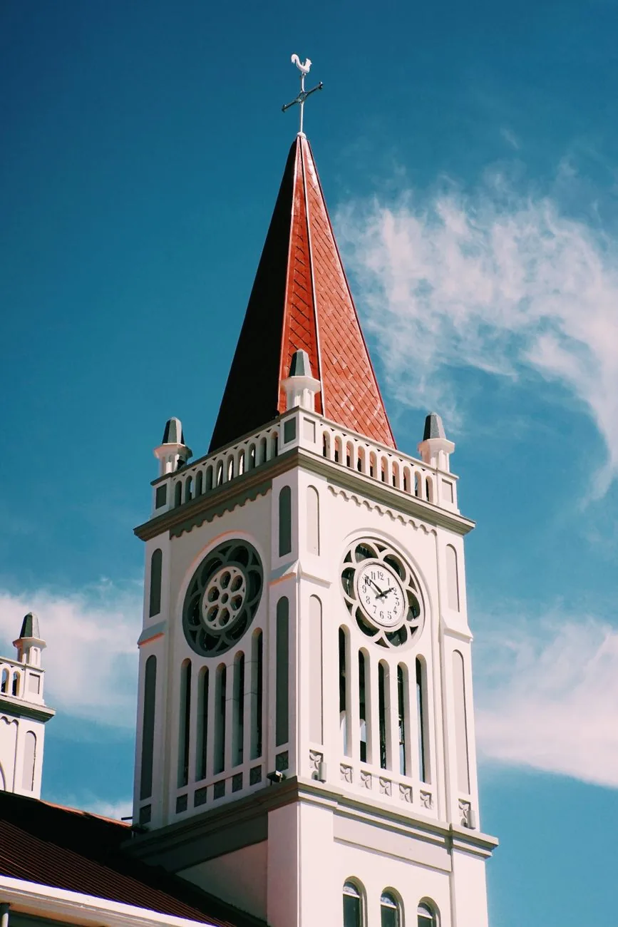 A pink tower of Our Lady of the Atonement Cathedral in Baguio with a rose window and pointed red roof