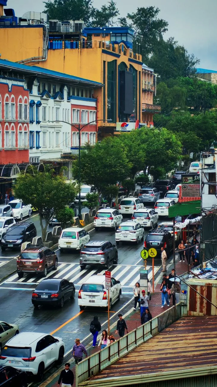 Traffic and colourful commercial buildings on a sloping street in central Baguio