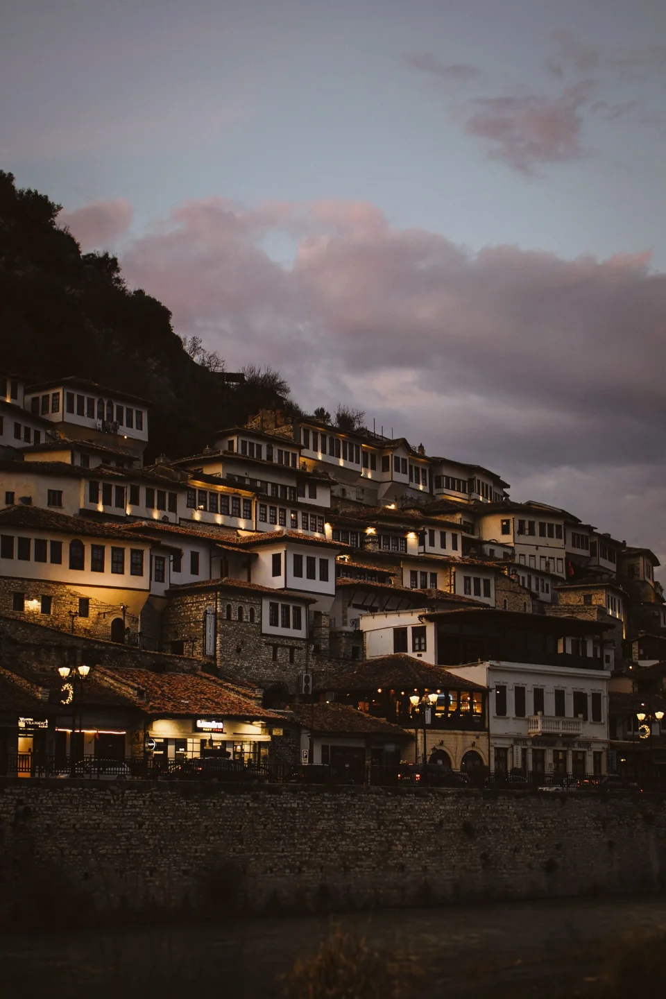 Mangalem’s white houses and river frontage in Berat at dusk