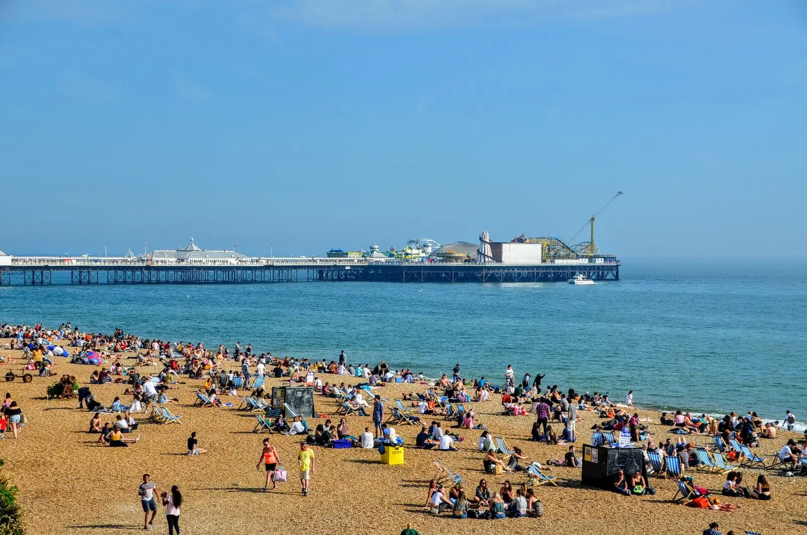 People on Brighton Beach near Palace Pier on a sunny day