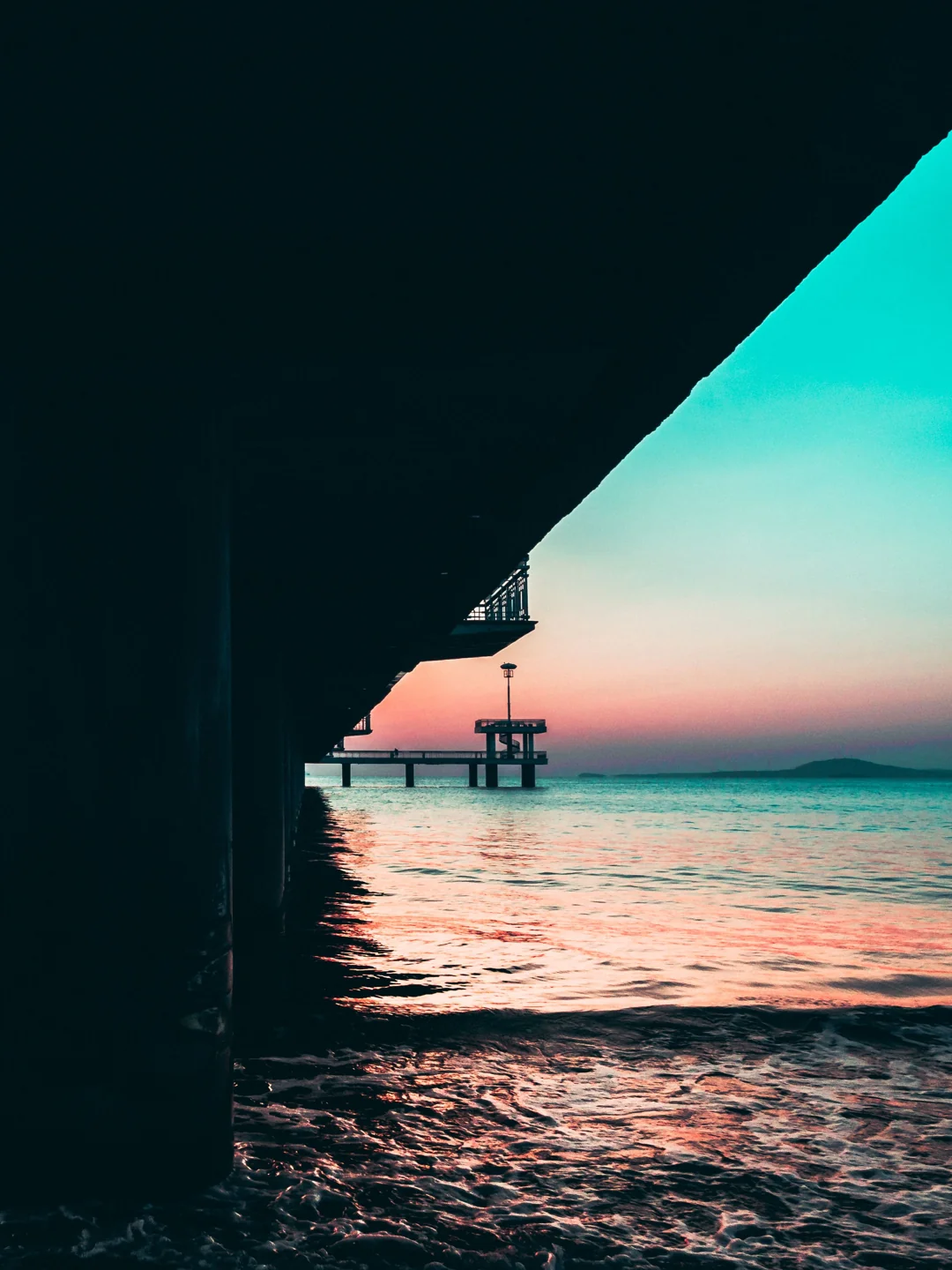 The structure of Burgas Pier silhouetted above the sea at sunrise
