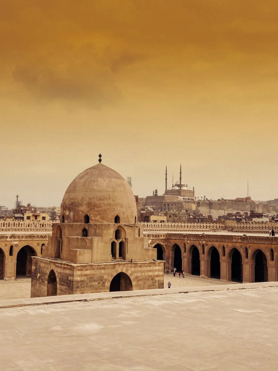 Ibn Tulun Mosque’s domed courtyard fountain and surrounding arcades in warm evening light