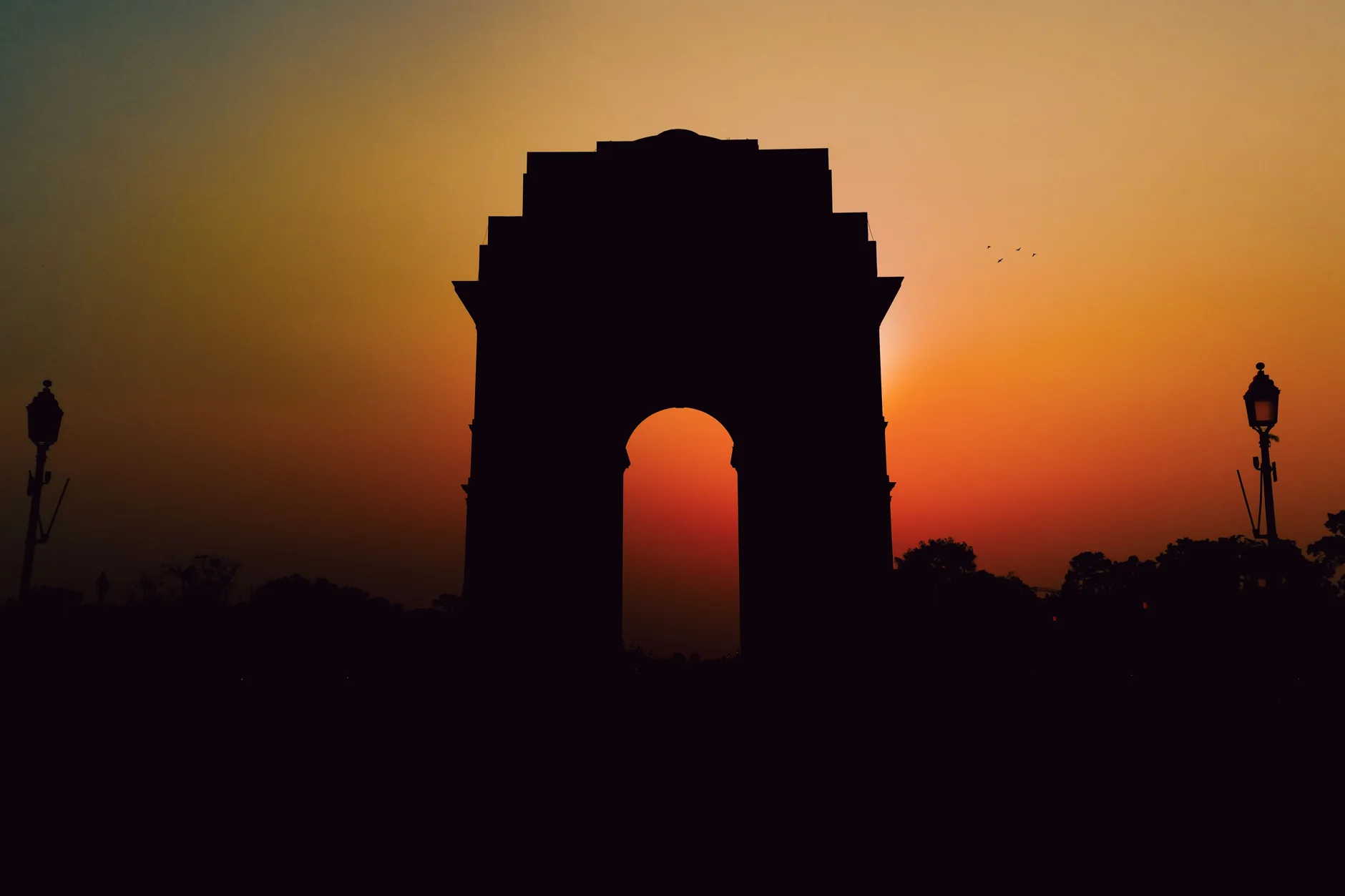 India Gate silhouetted against an orange sunset in New Delhi