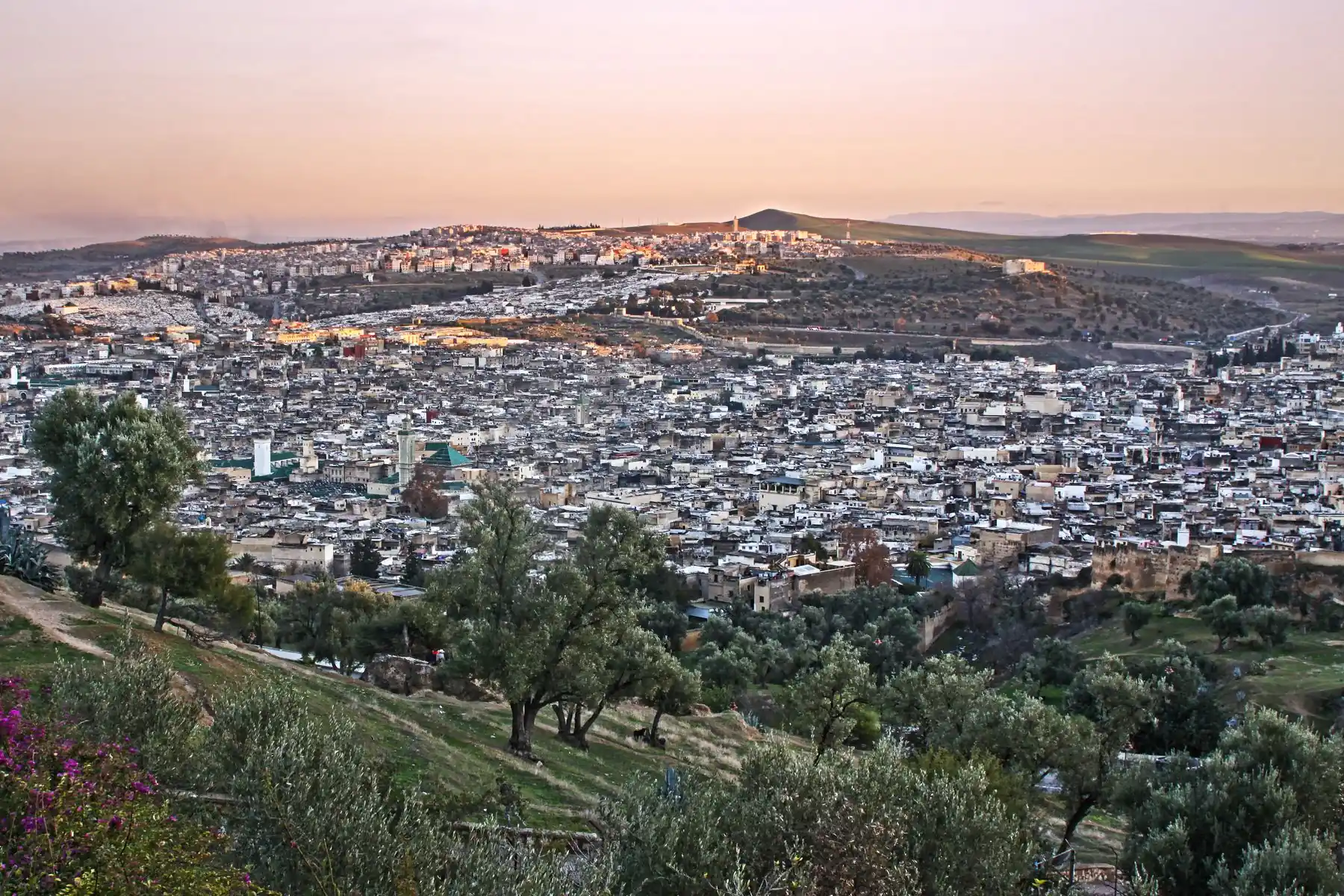 Beautiful sunset view over Fes, Morocco with a sprawling cityscape and hills in the background.