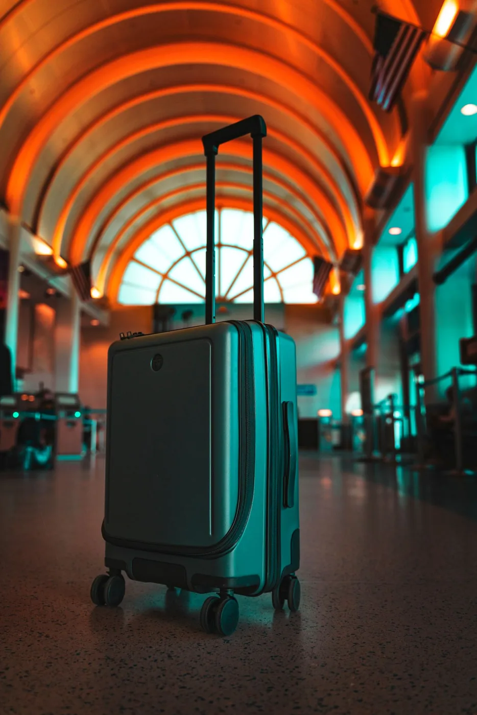 A suitcase beneath a curved orange canopy in an airport terminal