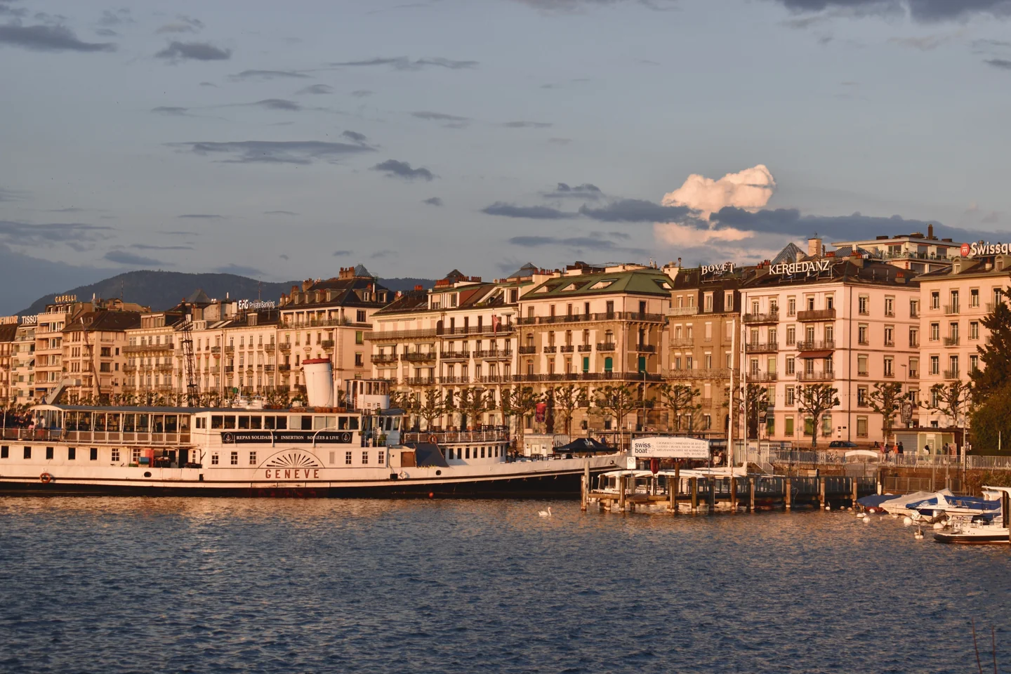 Sunset light on Geneva’s historic waterfront and moored passenger boats