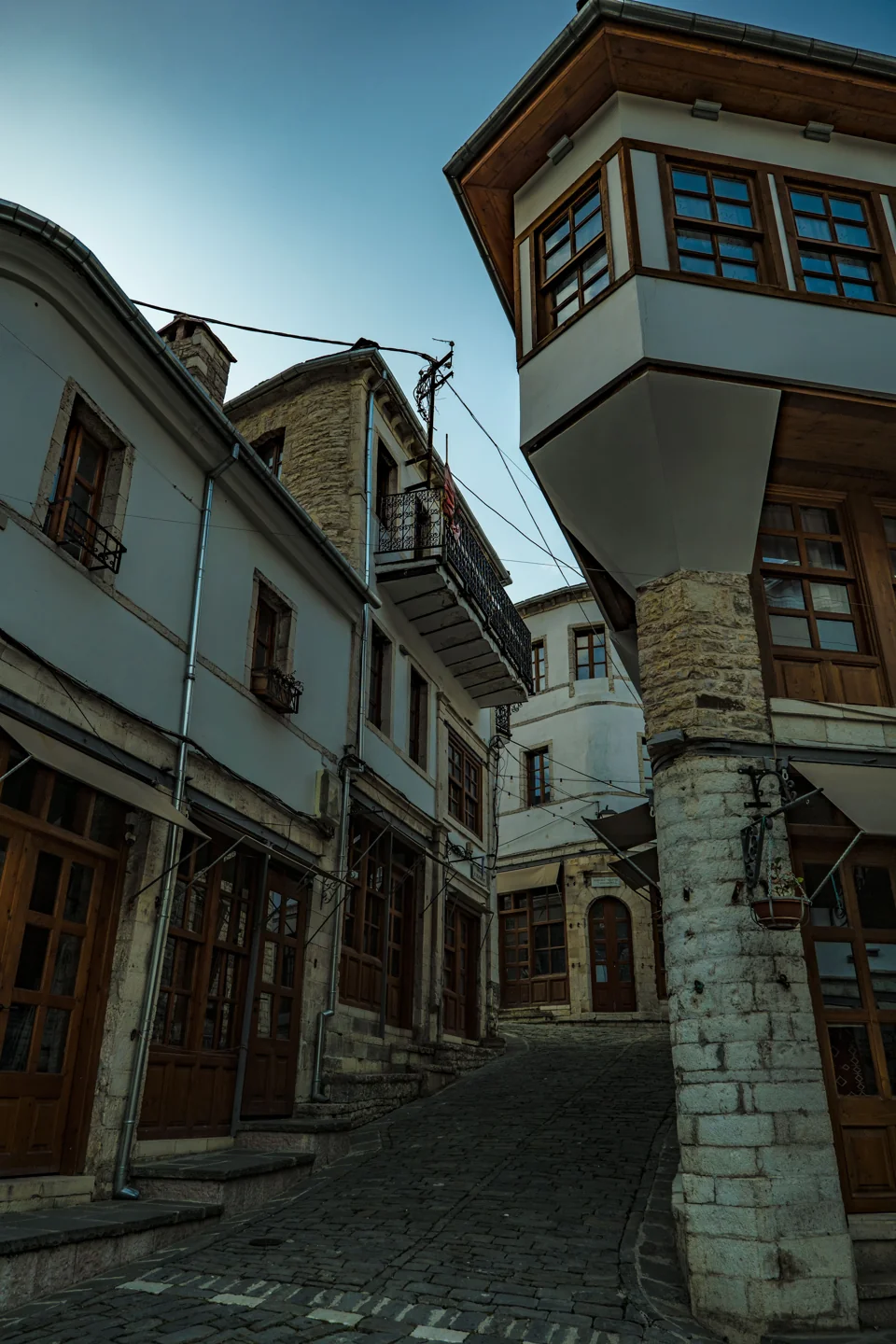 Stone-paved Gjirokastër bazaar lane between white house fronts and projecting wooden windows