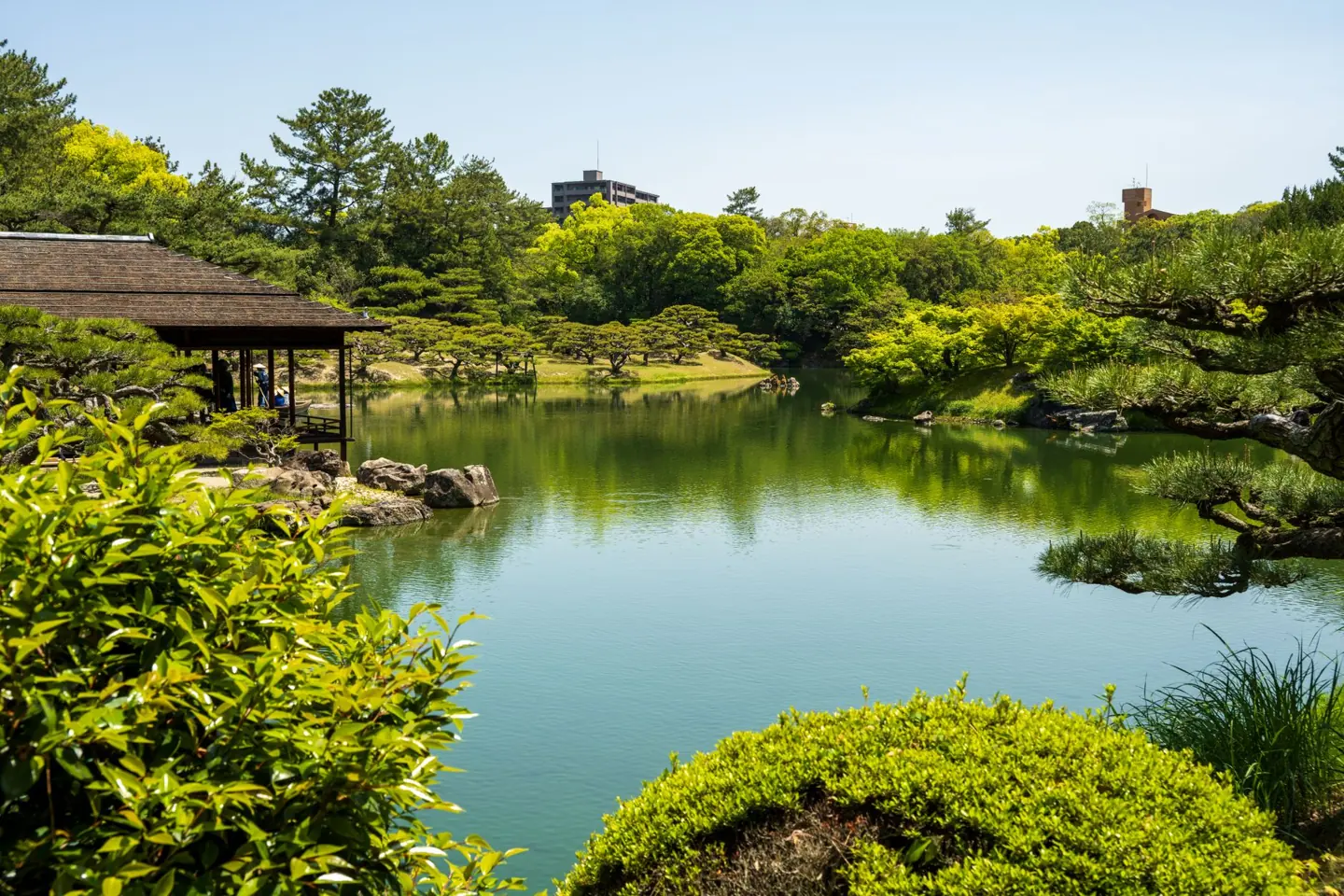 Shukkeien’s central pond, clipped shrubs and waterside pavilion reflected in the water