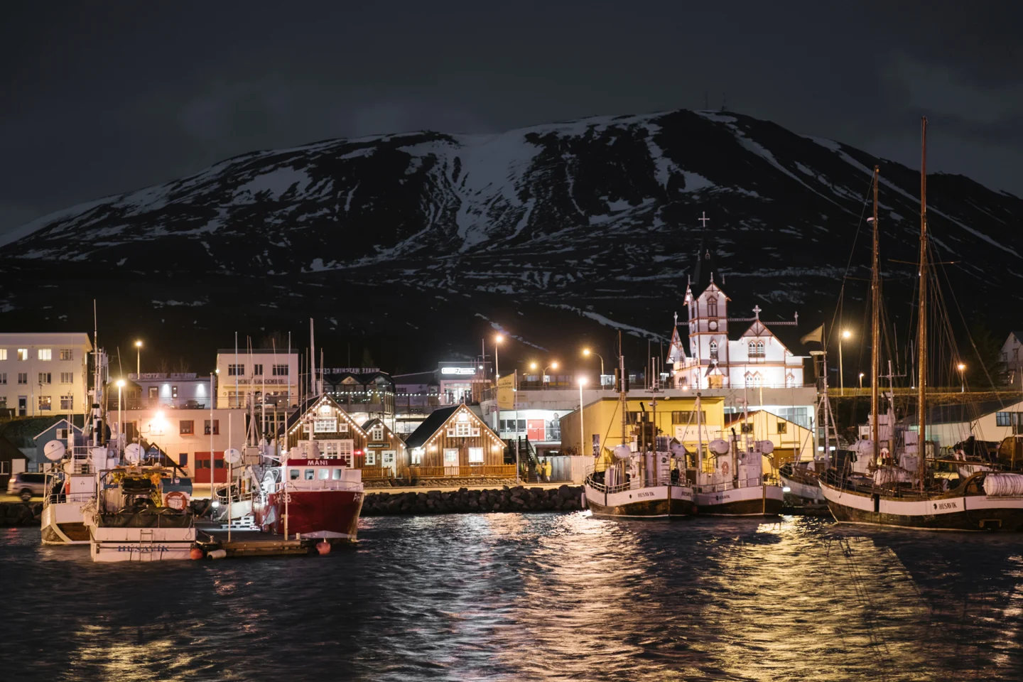 Húsavík harbour boats and waterfront buildings lit in the late evening