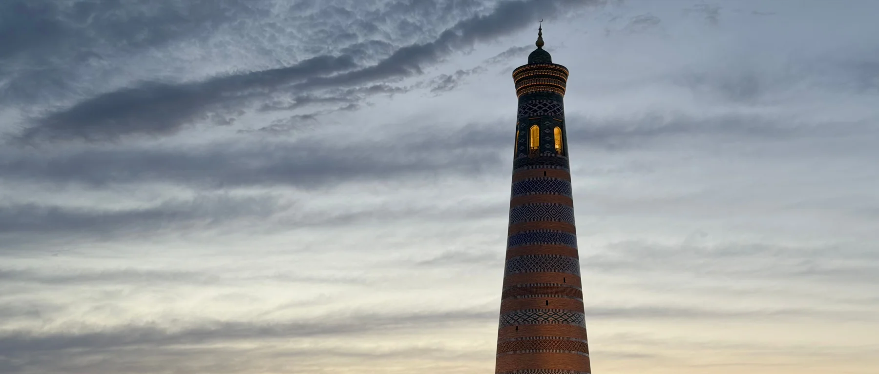 Islam Khoja Minaret above the rooftops of Khiva at sunset