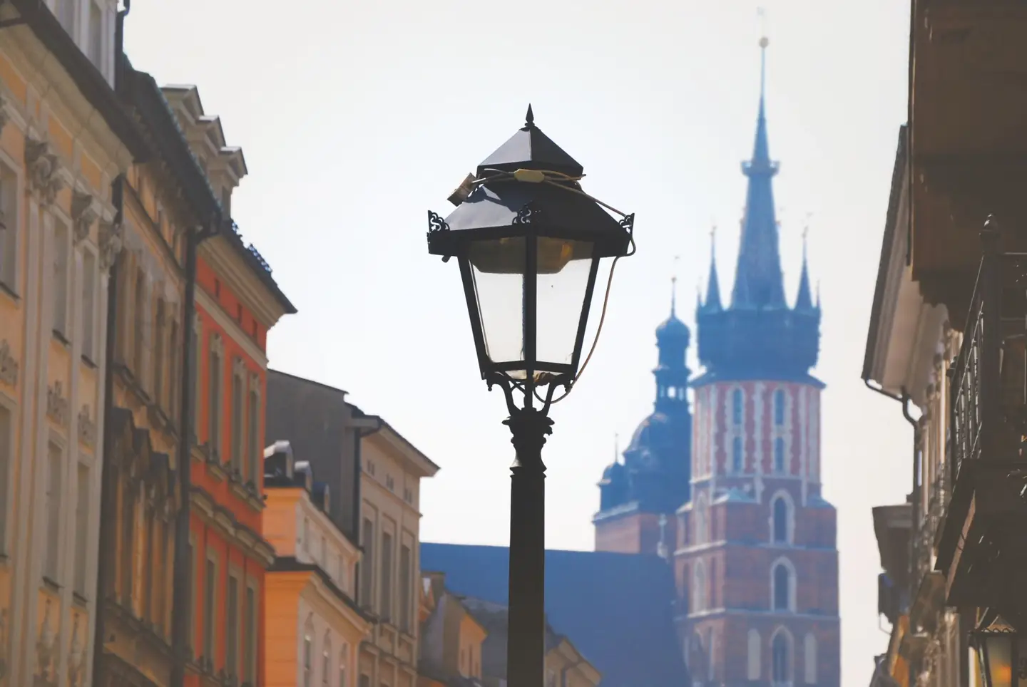 St Mary’s Basilica towers seen along a Kraków Old Town street behind a historic lamp