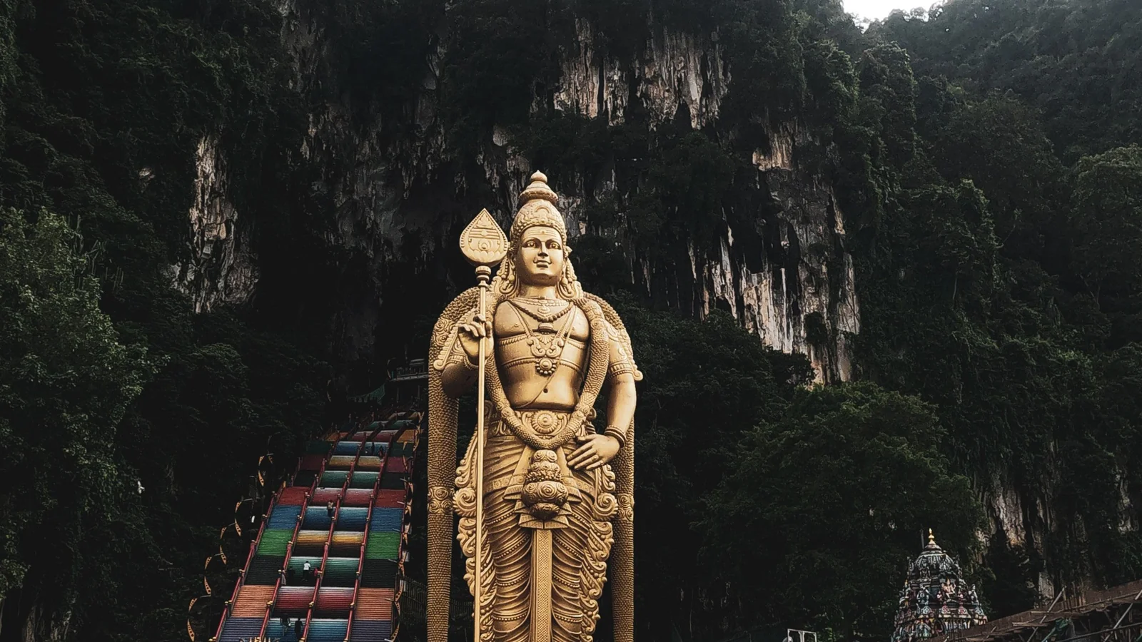 Lord Murugan’s golden statue and the rainbow staircase below the limestone cliff at Batu Caves.