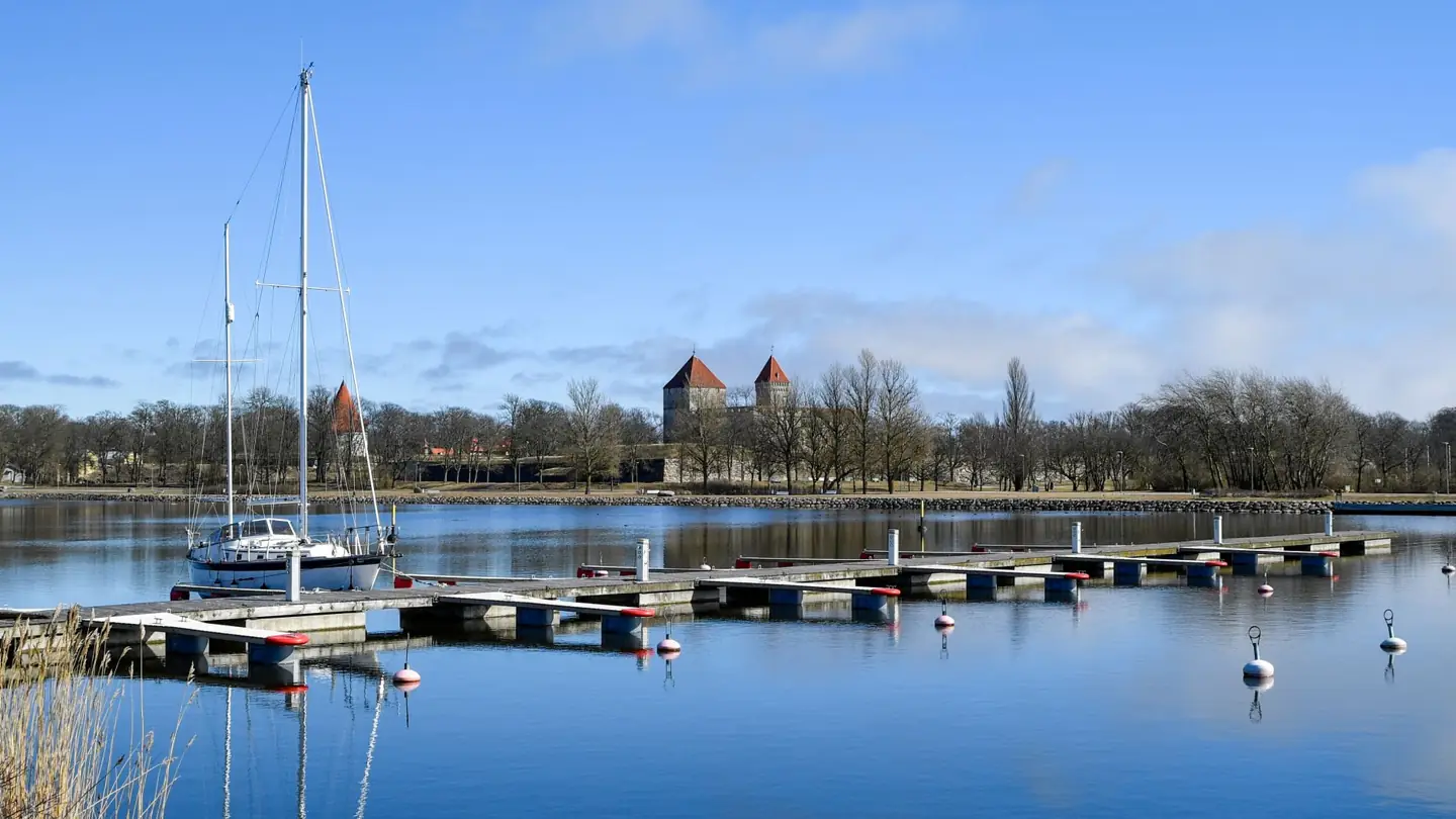 A sailboat and floating pontoons at Kuressaare City Harbour, with the castle’s square towers beyond