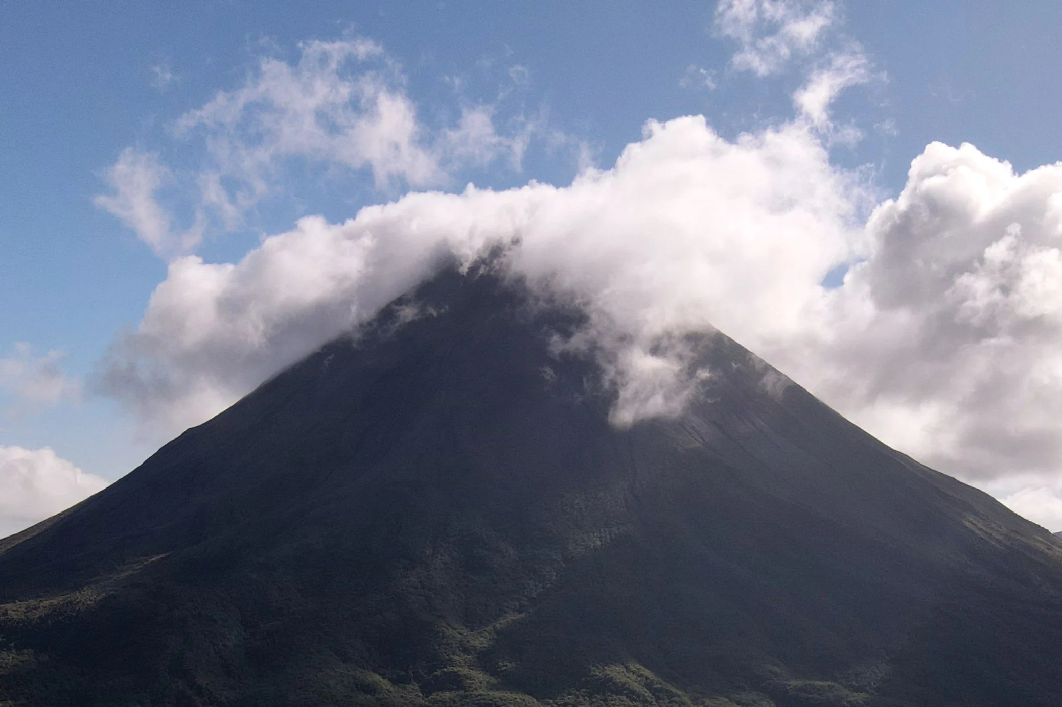 Arenal Volcano’s cloud-covered cone and forested lower slopes