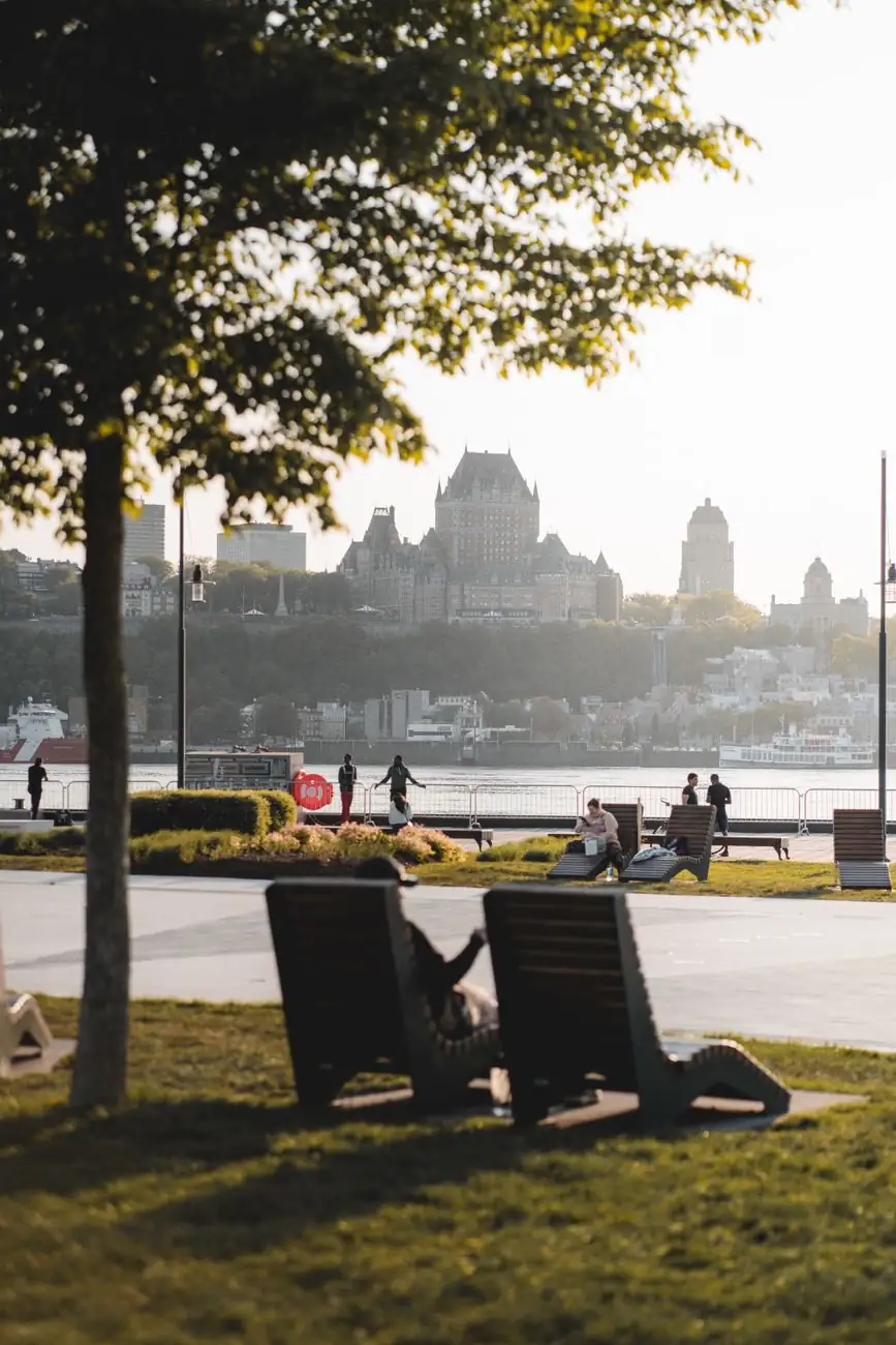 People resting beside the river in Lévis with Château Frontenac on the opposite Québec shore