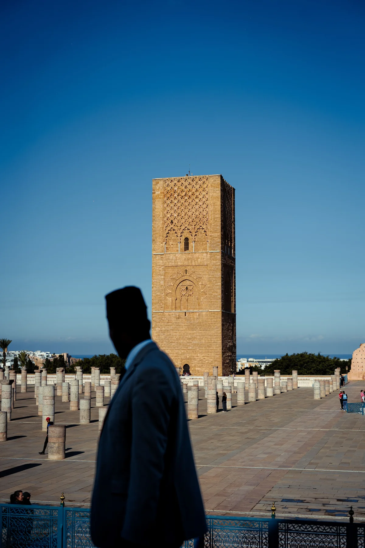 Hassan Tower and the surviving mosque columns in Rabat, with a passer-by in the foreground