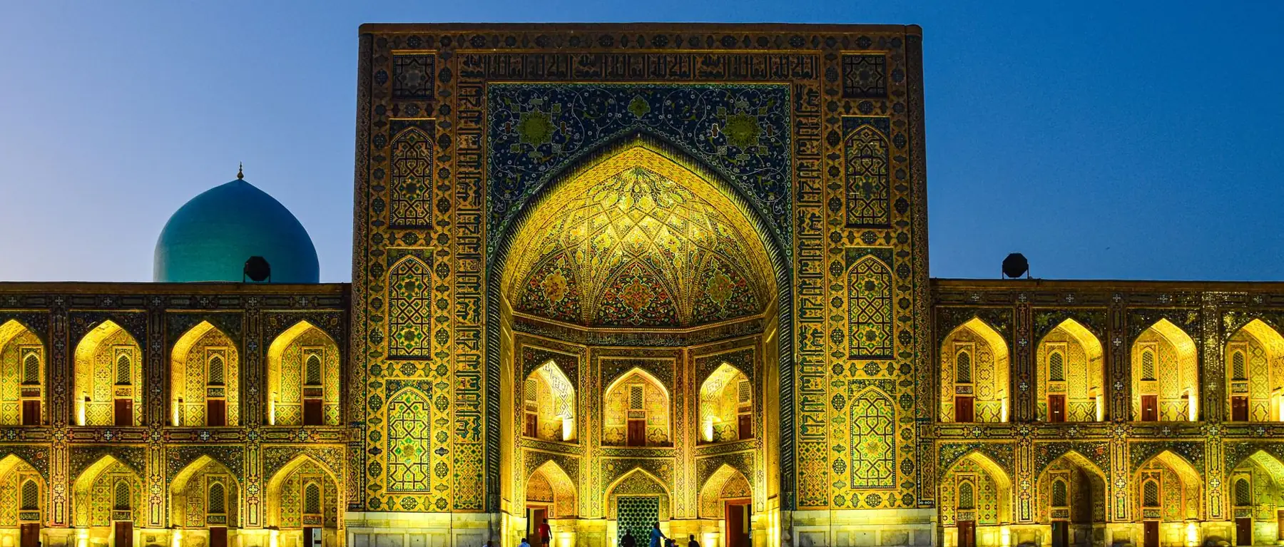Tilya-Kori Madrasa illuminated at dusk on Registan Square in Samarkand