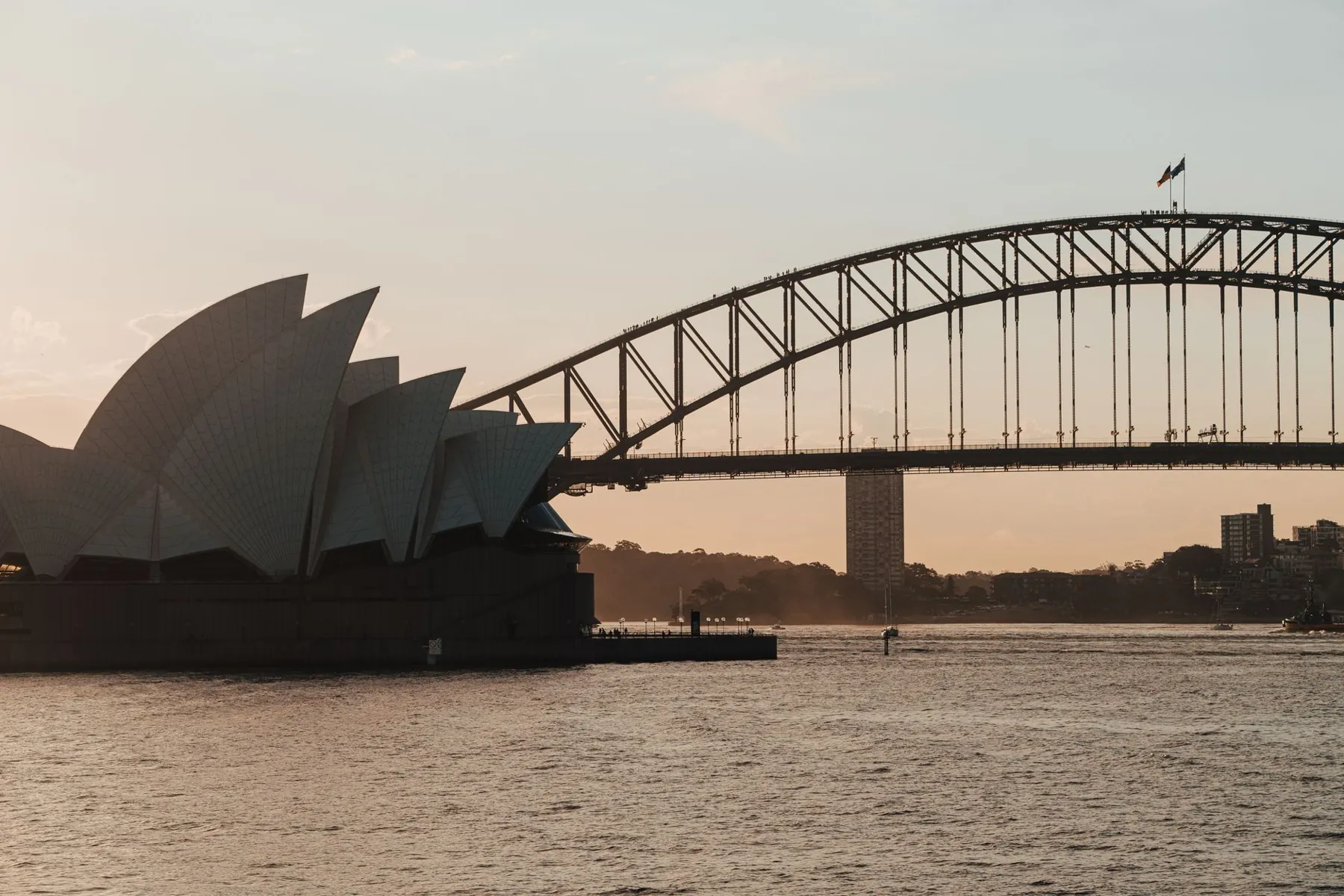 Sydney Opera House and Harbour Bridge across the harbour at sunset