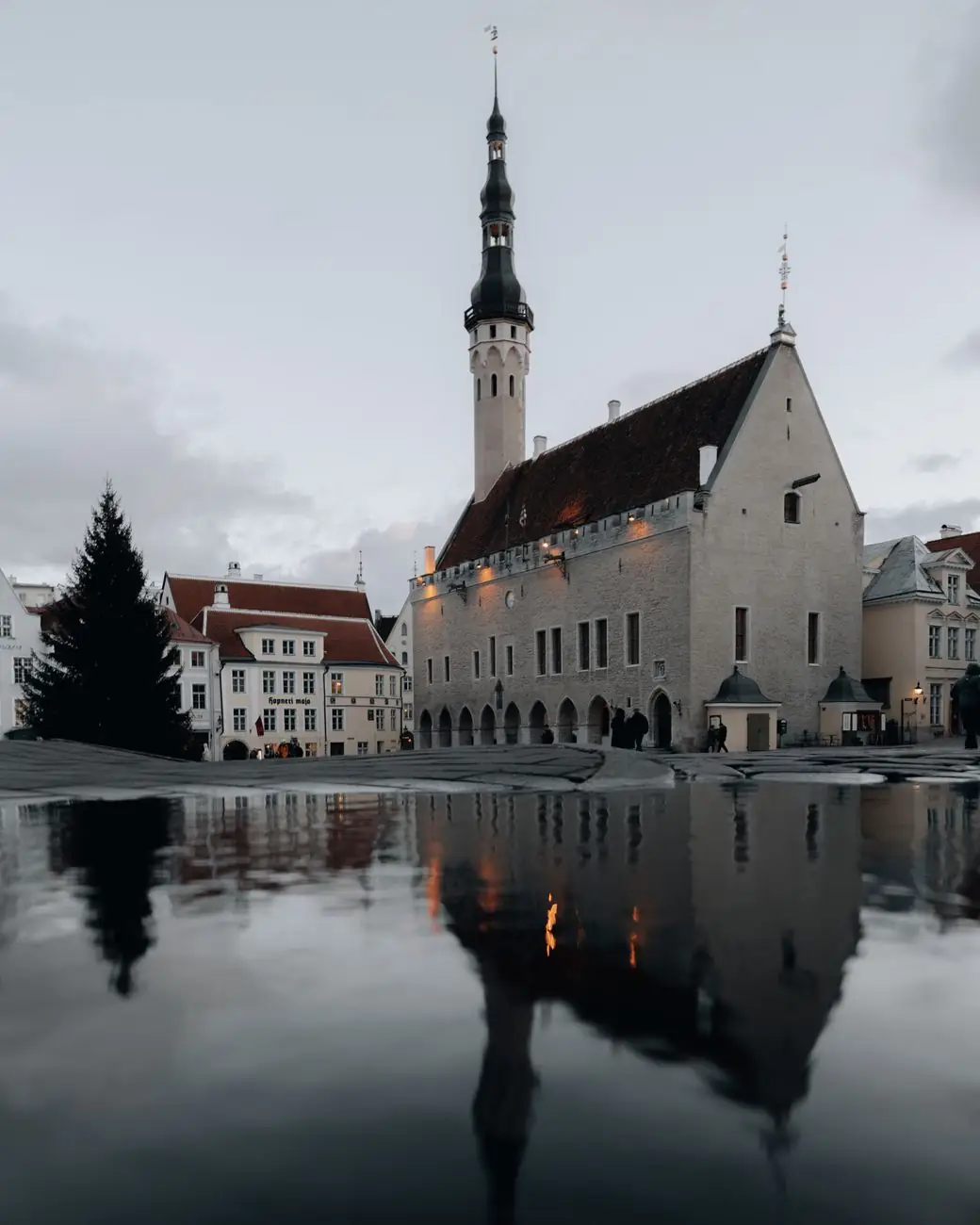 Tallinn Town Hall and its tower reflected in a puddle across Town Hall Square