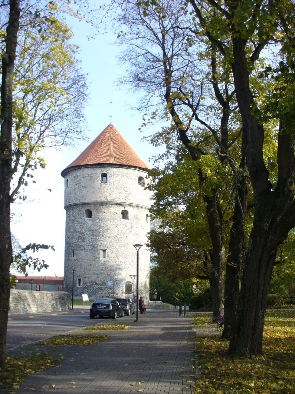 Tallinn’s round Kiek in de Kök stone tower with a red conical roof beside a tree-lined path
