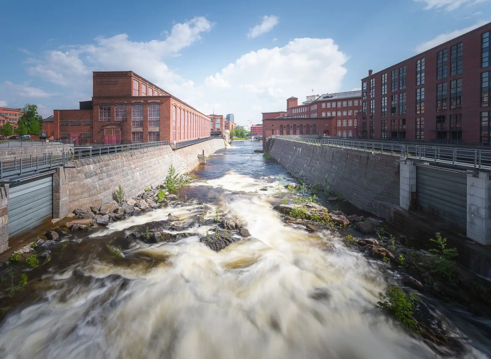 Explore the scenic Tammerkoski rapids with historic brick buildings in Tampere, Finland.
