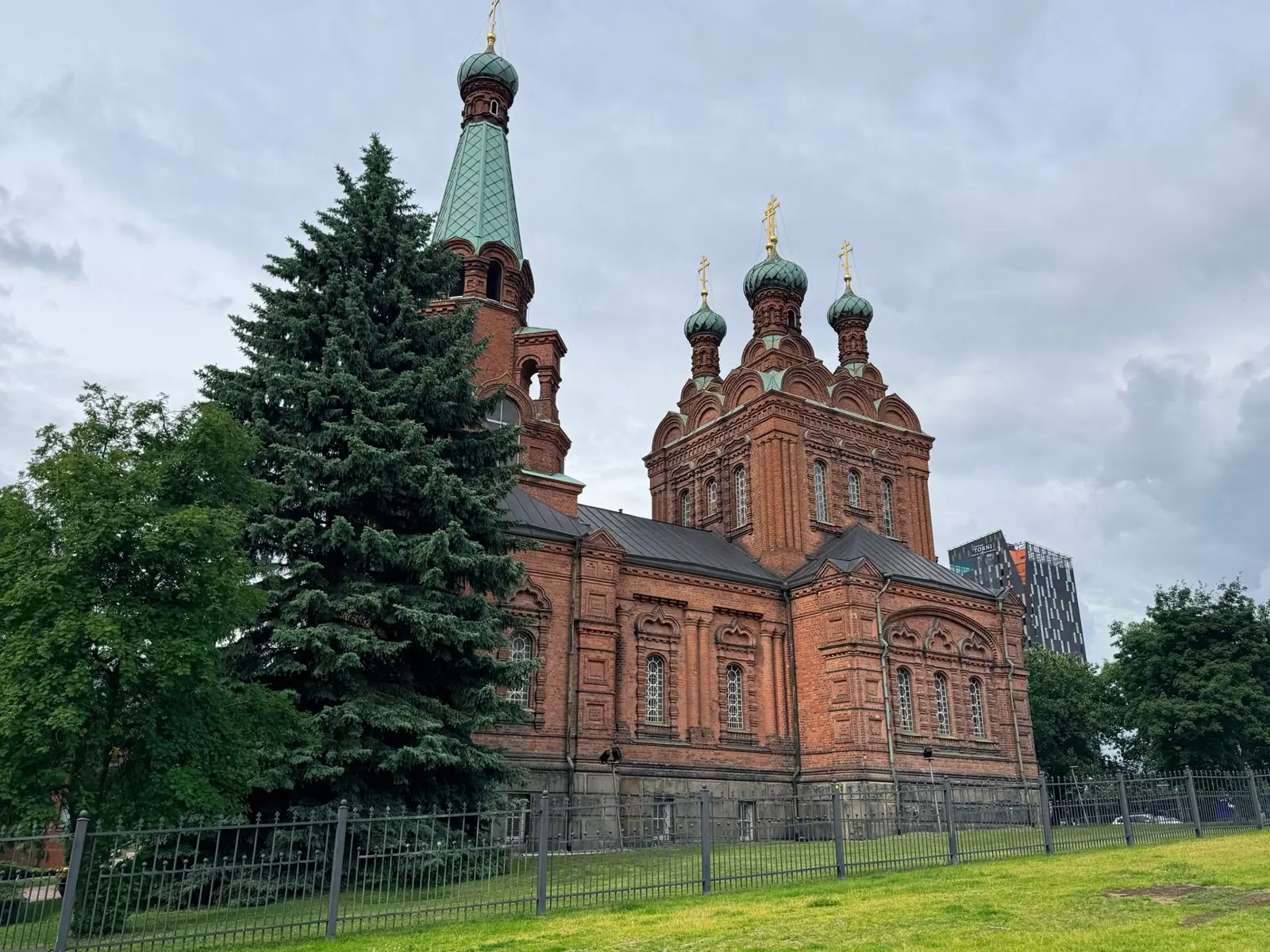 Beautiful view of Tampere Orthodox Church showcasing its red brick architecture against a cloudy sky.