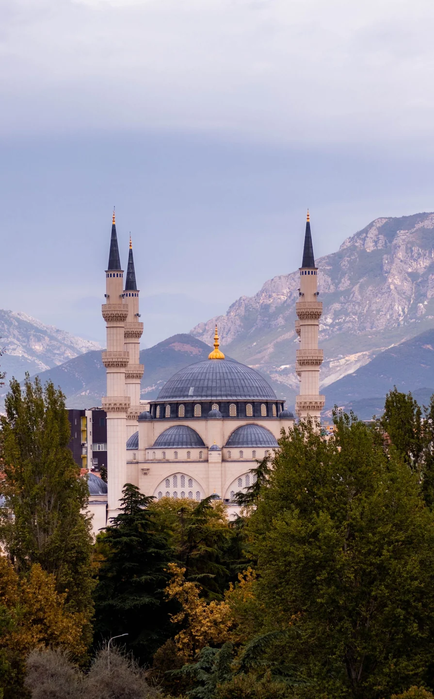 Namazgah Mosque domes and minarets seen through trees in Tirana
