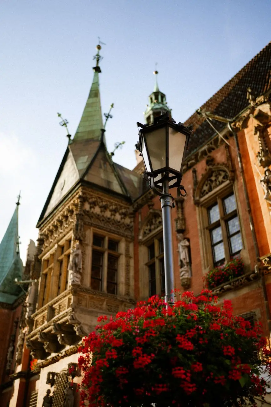 Carved projecting windows and Gothic details of Wrocław’s Old Town Hall beside a street lamp and flowers