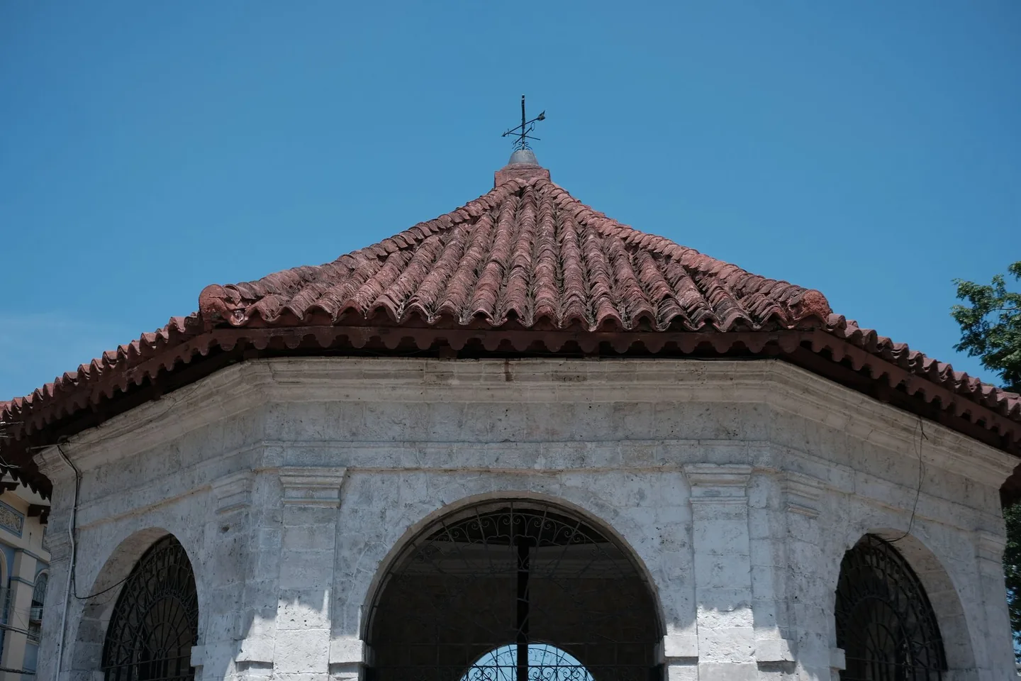 Red-tiled roof and stone arches of Magellan’s Cross Pavilion in Cebu City