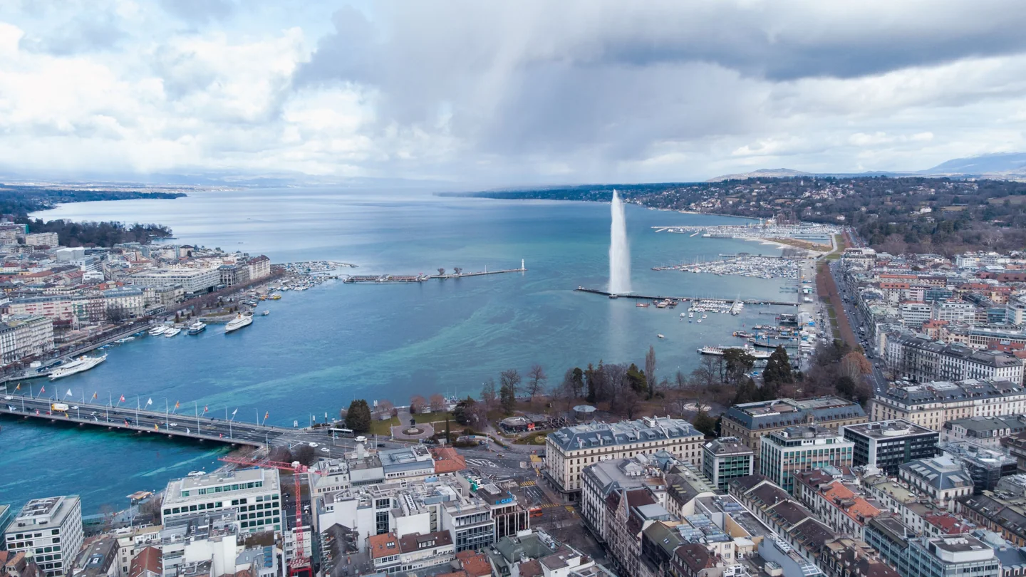 Geneva’s harbour and Jet d’Eau seen from above, with the old town beside the lake