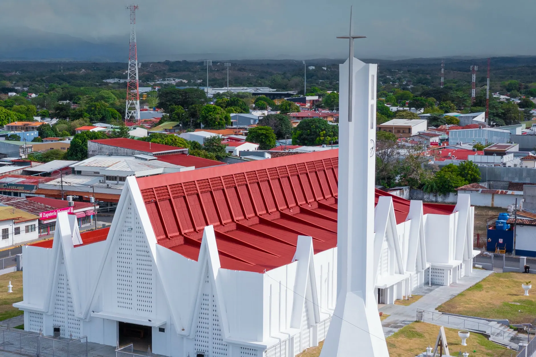 White angular Inmaculada Concepción church with its red roof and tall cross-topped tower in central Liberia, Costa Rica