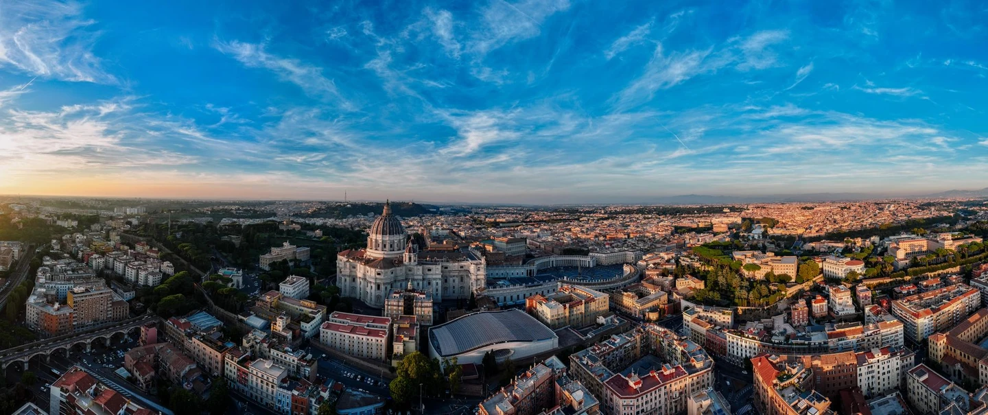 St Peter’s Basilica and its oval square amid the Rome skyline beneath a wide evening sky