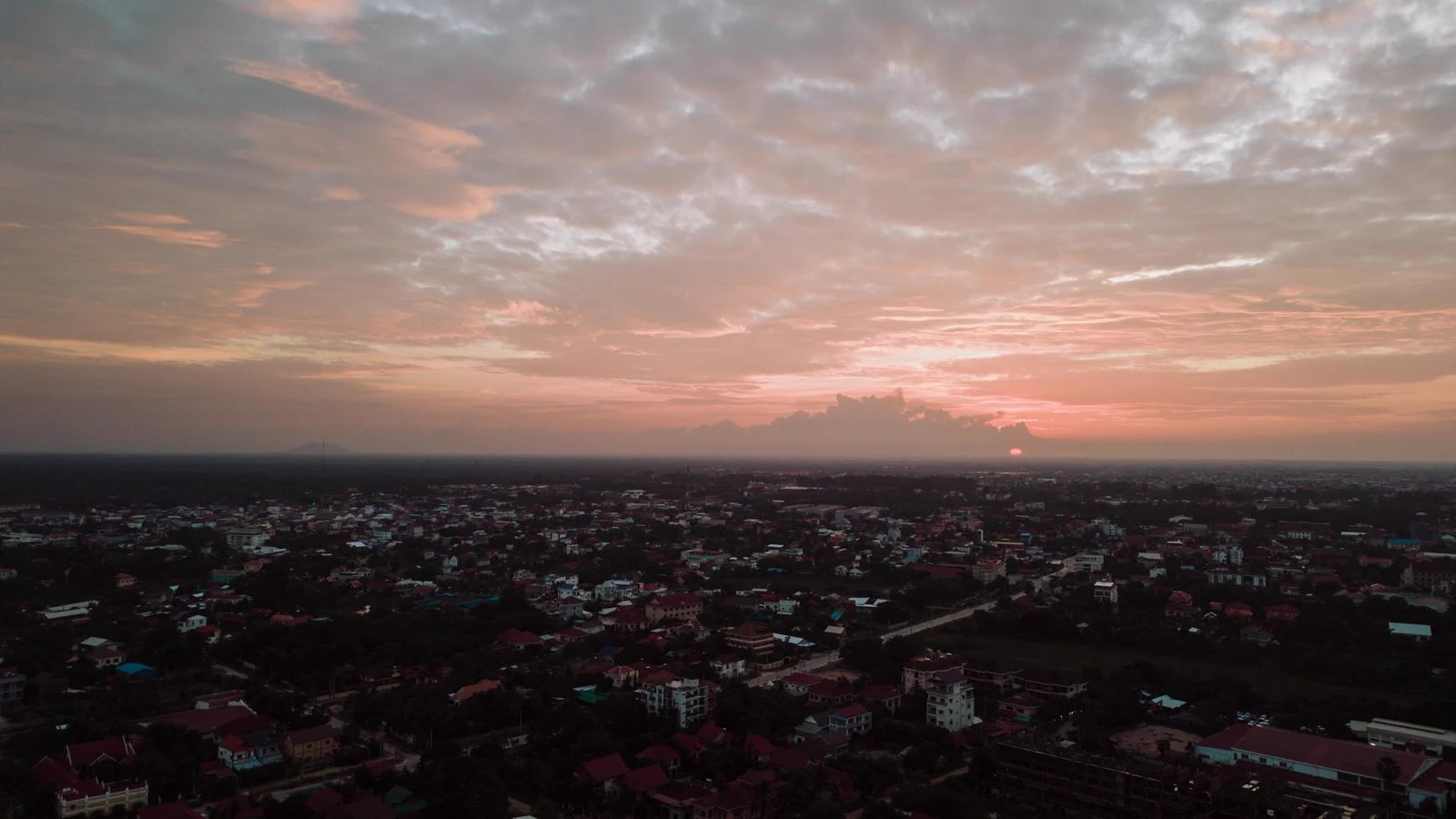 Siem Reap town at dusk beneath a broad clouded sky.