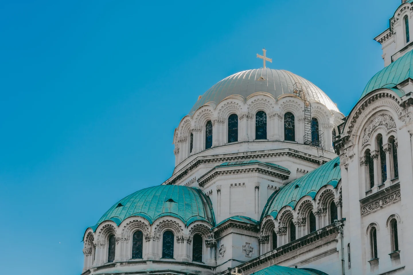 Green and gilded domes of Alexander Nevsky Cathedral in Sofia against a blue sky