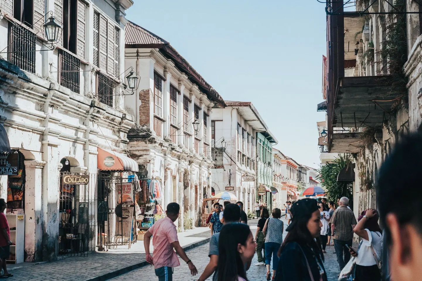 Visitors walking between timber-fronted heritage houses and shops on Calle Crisologo in Vigan