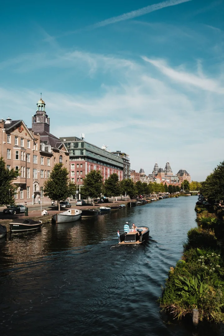 An Amsterdam canal with boats and historic waterfront buildings
